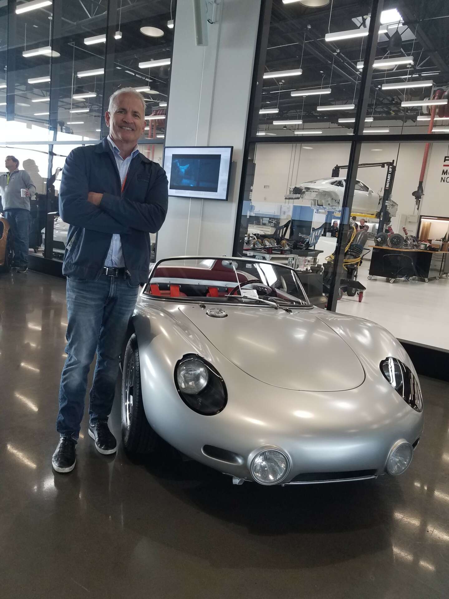 Dean Morash next to a Porsche race car at the Porsche Experience